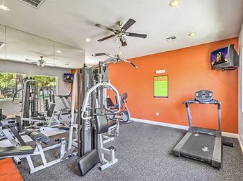 A gym with exercise equipment and a ceiling fan